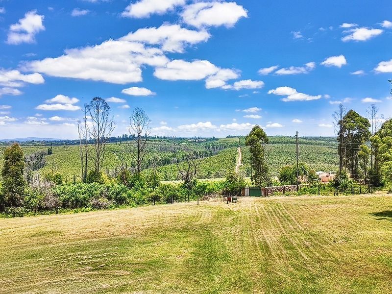 Expansive rural landscape view overlooking rolling hills and agricultural land, featuring open pasture and perimeter fencing.