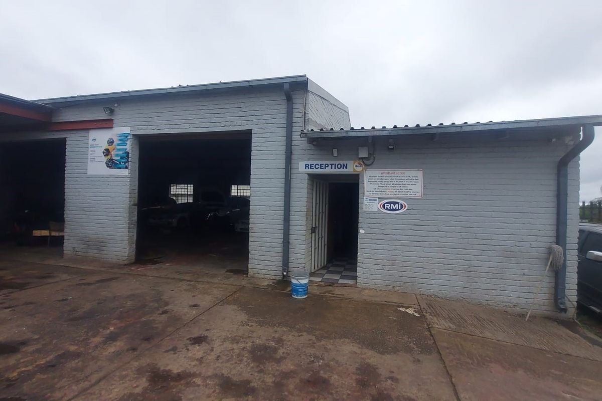 Front elevation of an industrial workshop featuring a reception entrance and large vehicle access bay with painted brick exterior.