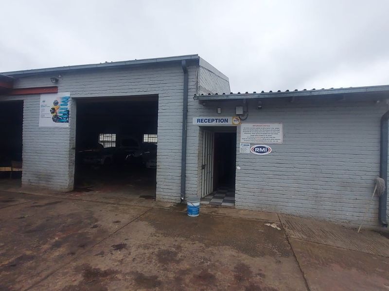 Front elevation of an industrial workshop featuring a reception entrance and large vehicle access bay with painted brick exterior.