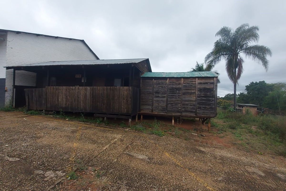 Exterior view of a timber-clad industrial structure featuring a raised deck and corrugated metal roofing, situated on a concrete and dirt yard.