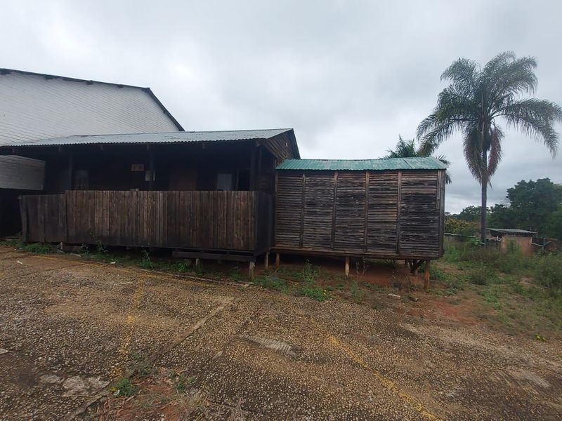 Exterior view of a timber-clad industrial structure featuring a raised deck and corrugated metal roofing, situated on a concrete and dirt yard.