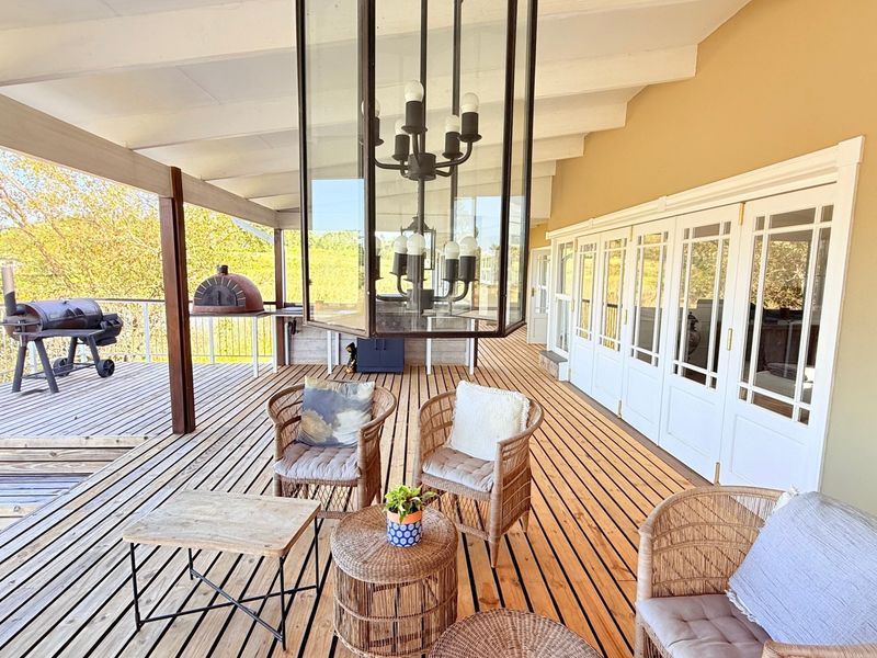 Spacious covered timber deck featuring a built-in pizza oven, large glass panel doors, and expansive outdoor living space with scenic views.