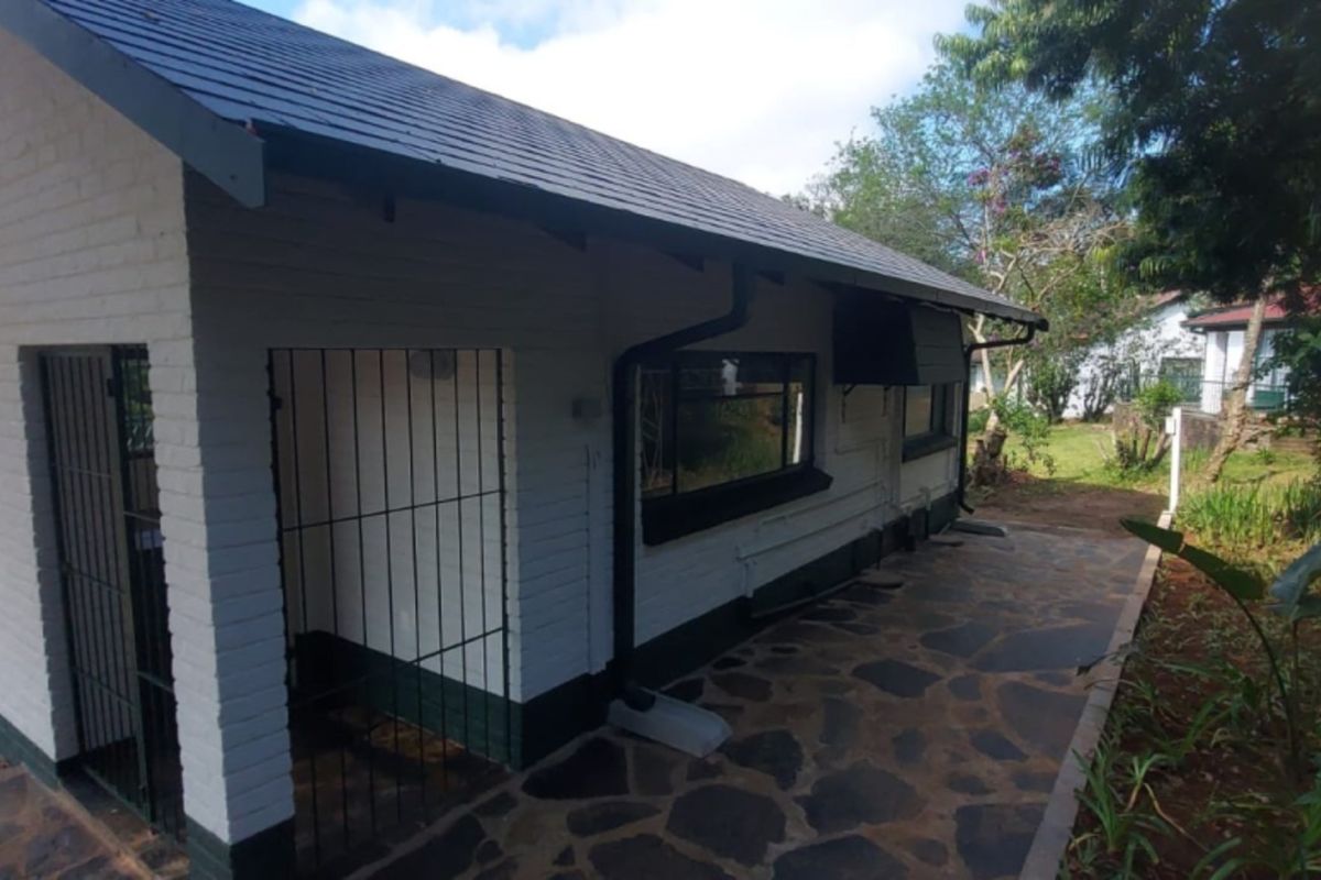 Rear exterior view of the lodge featuring a stone paved patio, painted brick walls, and secure metal gate access.