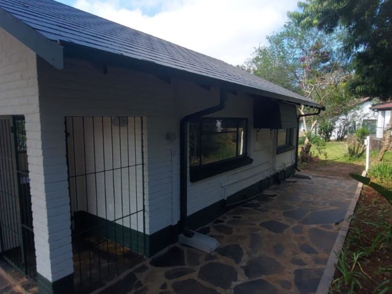 Rear exterior view of the lodge featuring a stone paved patio, painted brick walls, and secure metal gate access.