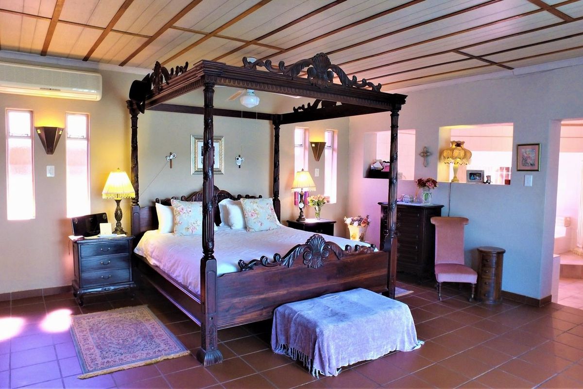 Spacious bedroom featuring a timber-paneled ceiling, tiled flooring, and integrated wall niches, with an adjoining en-suite bathroom area visible.