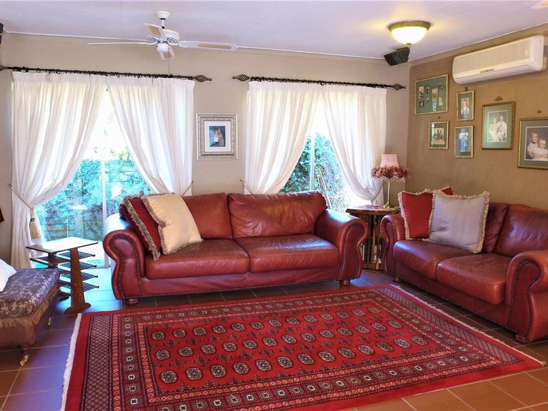 Spacious living room featuring tiled flooring, a ceiling fan, and a wall-mounted split-system air conditioner with direct access to the garden through sliding doors.
