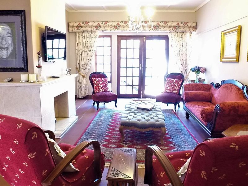 A traditional living room featuring a central fireplace, tiled flooring, and double french doors providing access to the exterior.