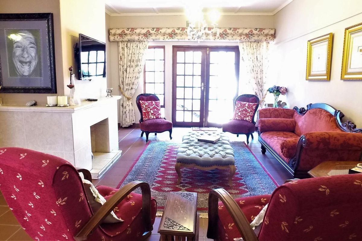 A traditional living room featuring a central fireplace, tiled flooring, and double french doors providing access to the exterior.