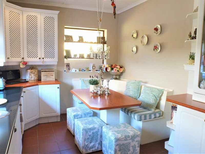 A cozy kitchen featuring white cabinetry, laminate countertops, a built-in breakfast nook, and tiled flooring, offering a functional and charming eat-in space.