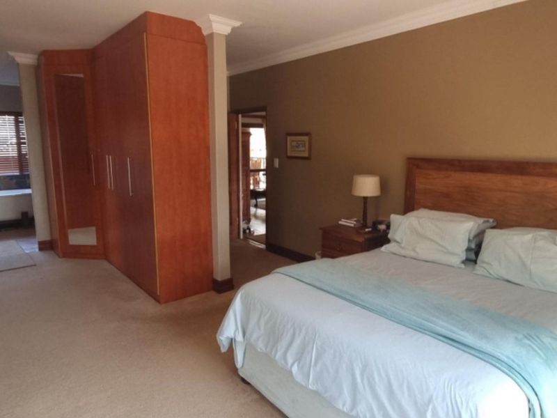 Spacious bedroom featuring built-in wooden cabinetry and an open-plan layout leading to an en-suite bathroom area with a freestanding bathtub.