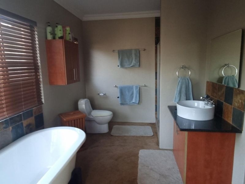 A functional bathroom featuring a freestanding bathtub, a vessel sink vanity with stone countertop, and a toilet.
