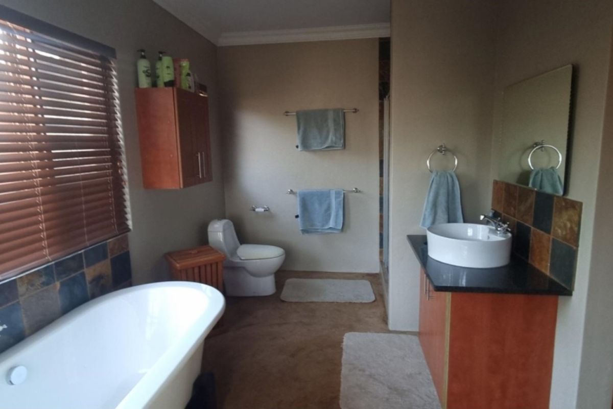 A functional bathroom featuring a freestanding bathtub, a vessel sink vanity with stone countertop, and a toilet.