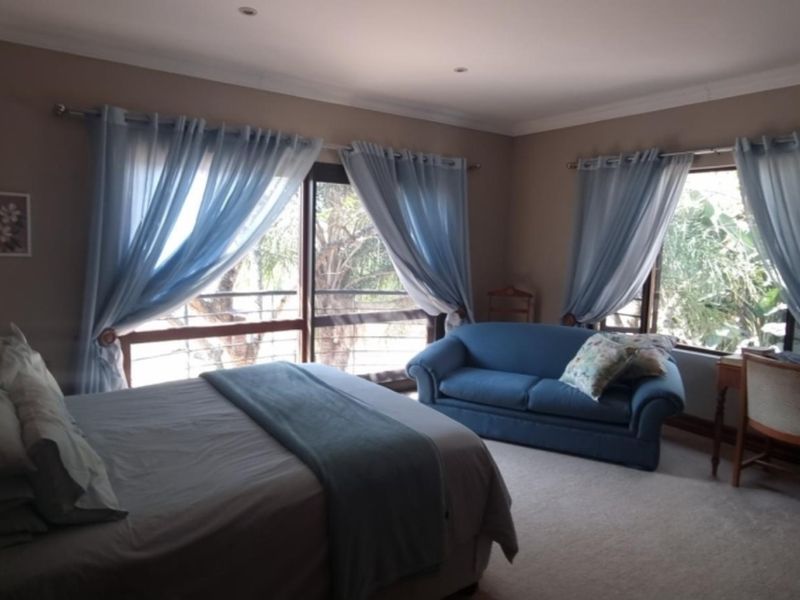 A spacious bedroom featuring neutral wall tones, carpeted flooring, and large windows with natural light, offering a comfortable and functional living space.