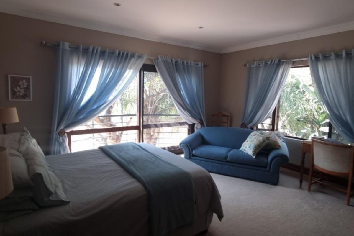 A spacious bedroom featuring neutral wall tones, carpeted flooring, and large windows with natural light, offering a comfortable and functional living space.