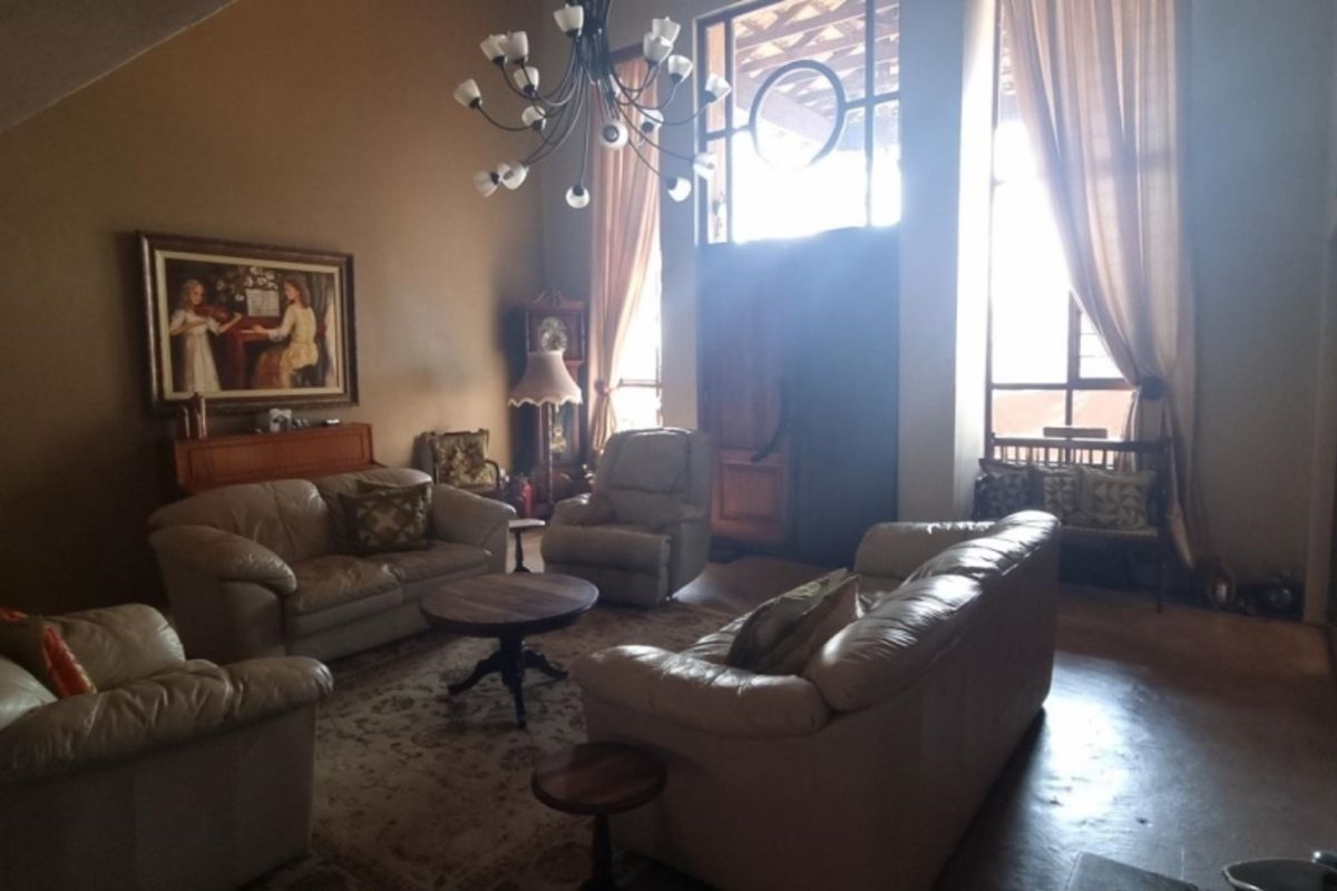 Spacious living room featuring high vaulted ceilings, large windows with natural light, and wood-paneled wall accents.