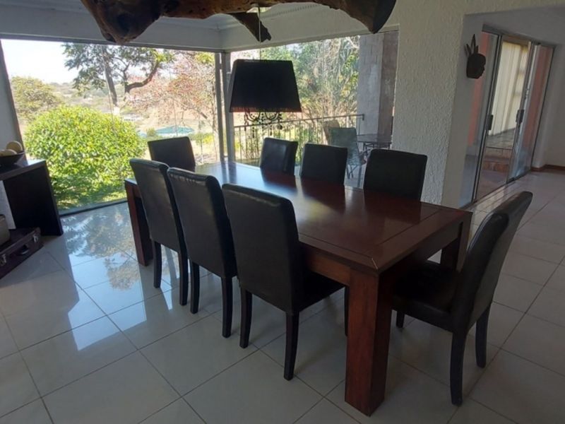 Spacious dining area featuring large glass windows with garden views, tiled flooring, and sliding door access to the patio.