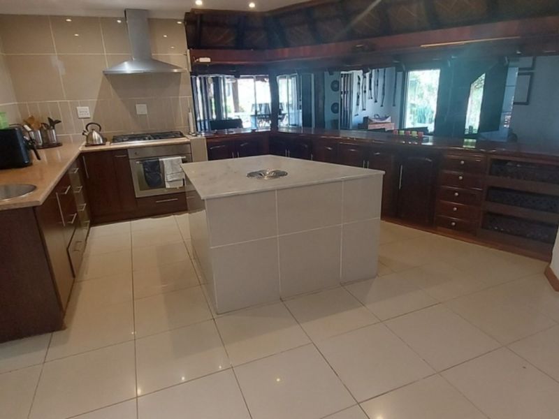 Spacious kitchen featuring dark wood cabinetry, a central island with a prep bowl, tiled flooring, and a stainless steel extractor fan.