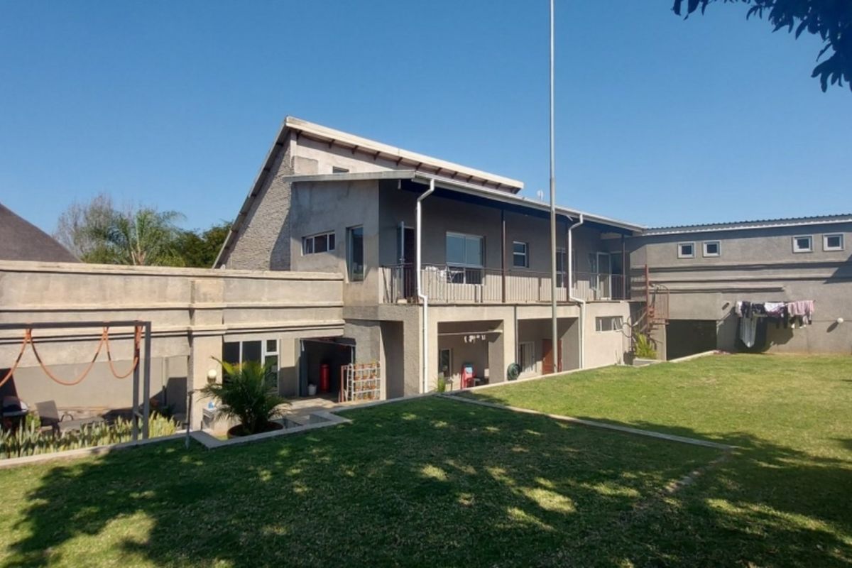 Rear view of the property featuring a multi-level structure, covered patio area, and a spacious lawn.