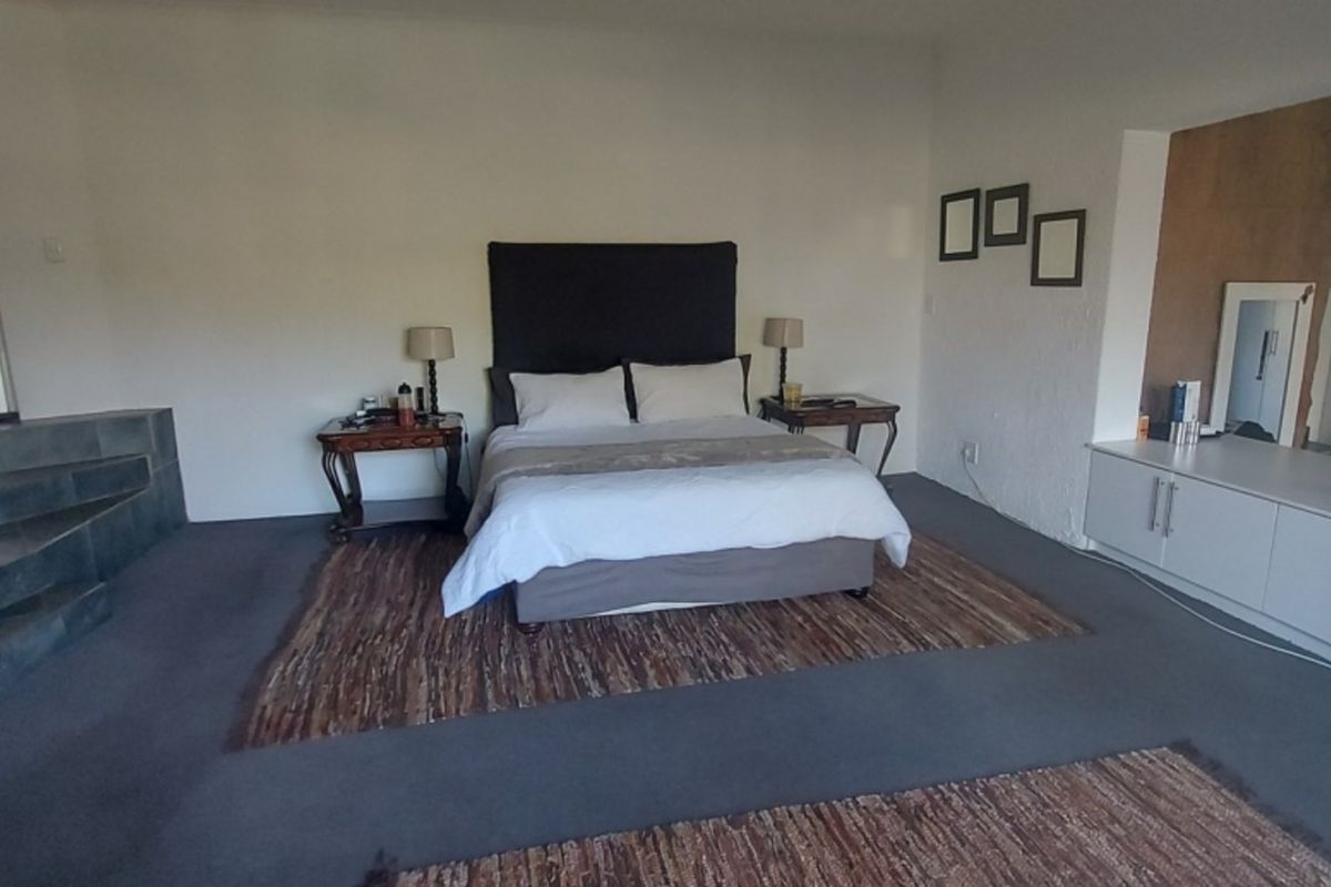 Spacious bedroom featuring a raised tiled platform area, built-in cabinetry, and direct access to an exterior door.