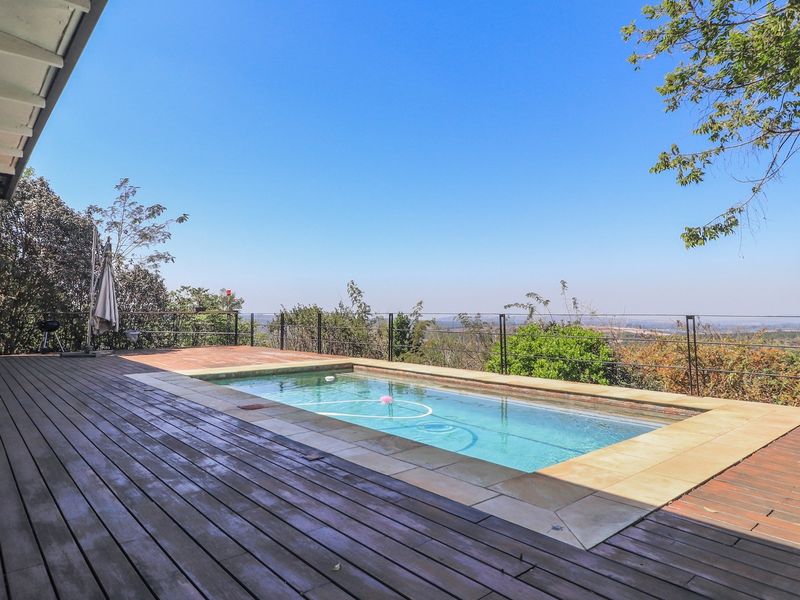 Outdoor pool area featuring timber decking, a swimming pool, and metal balustrades with expansive elevated views.