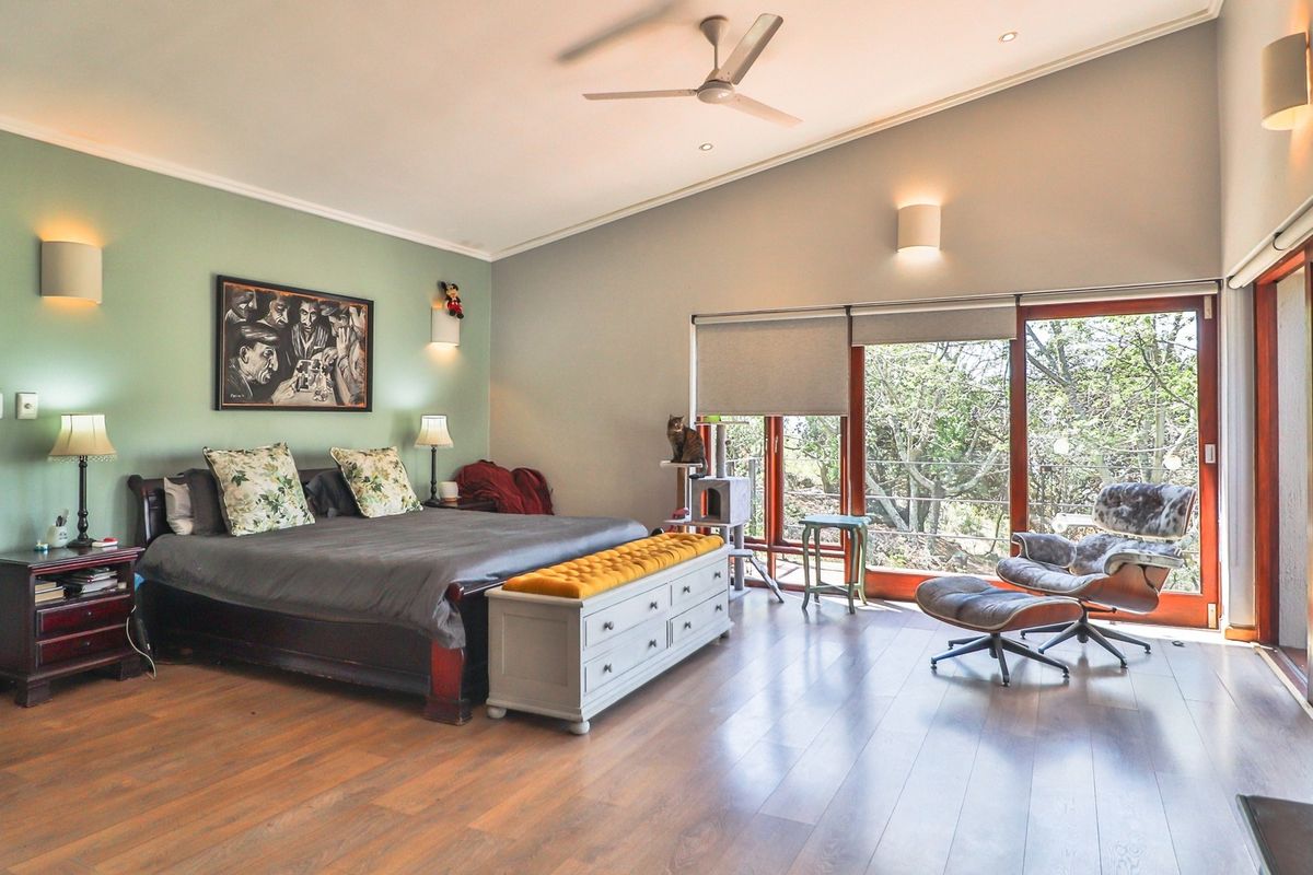 Spacious bedroom featuring laminate flooring, a vaulted ceiling with a fan, and large sliding glass doors that provide ample natural light and garden views.
