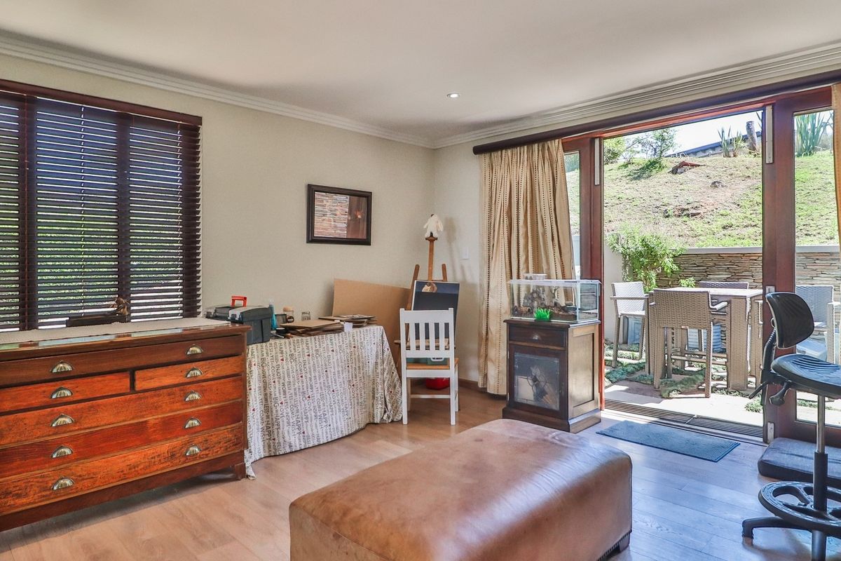 A bright living room featuring laminate flooring, recessed lighting, and large sliding glass doors that provide seamless access to an outdoor patio area.