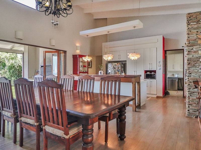 Spacious open-plan living and dining area featuring a striking stone-clad feature wall, exposed ceiling beams, and a modern kitchen with a central island.