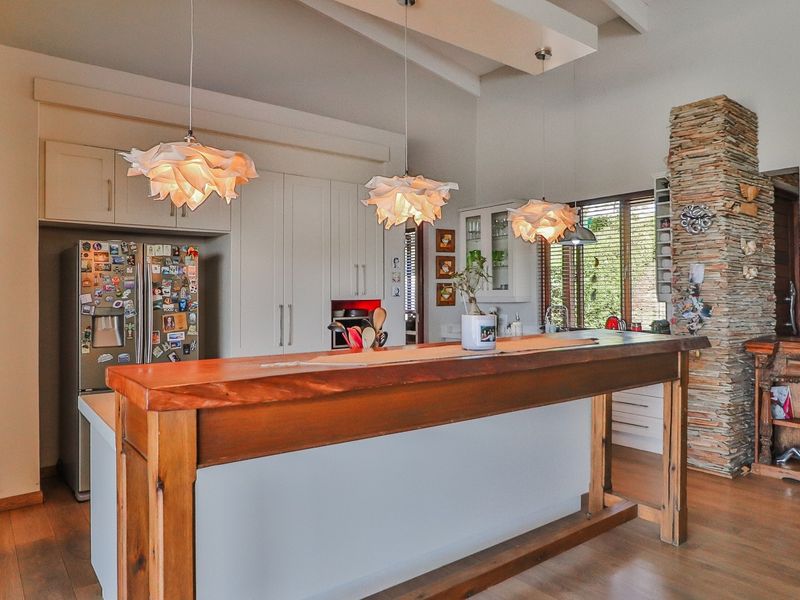 A well-appointed kitchen featuring a large timber-topped island, custom cabinetry, and a striking stone feature wall, complemented by warm timber flooring.