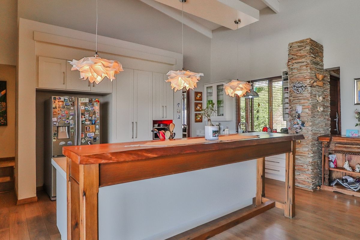 A well-appointed kitchen featuring a large timber-topped island, custom cabinetry, and a striking stone feature wall, complemented by warm timber flooring.