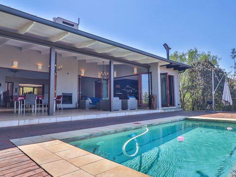 Spacious outdoor entertainment area featuring a swimming pool, timber decking, and a large covered patio with bi-fold doors leading into the main living space.