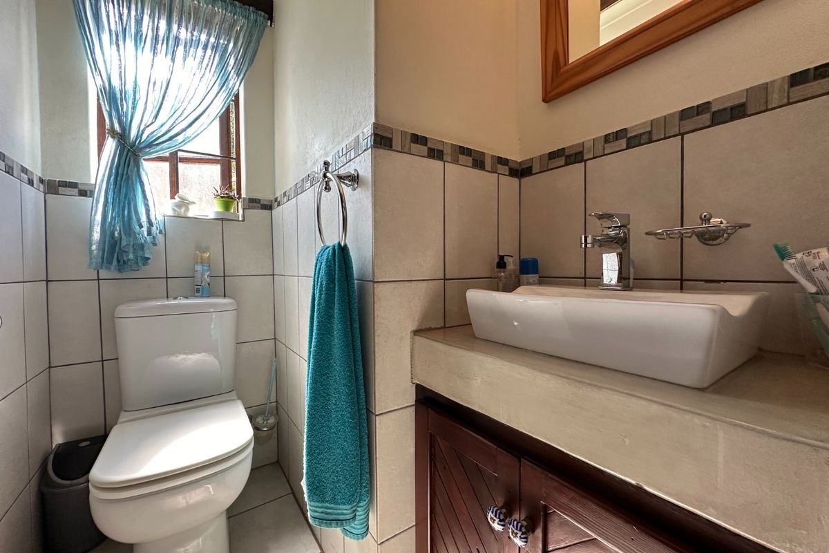 A compact bathroom featuring a vessel sink on a custom vanity, tiled walls with decorative border, and a standard toilet.