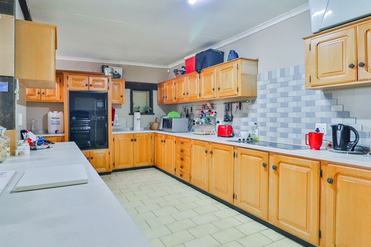 A functional kitchen featuring extensive wooden cabinetry, tiled backsplash, and ample countertop workspace, suitable for a busy farm household.