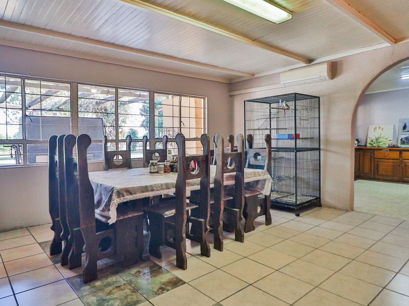 Spacious dining area featuring tiled flooring, large windows for natural light, and an arched entryway leading to an adjacent room.