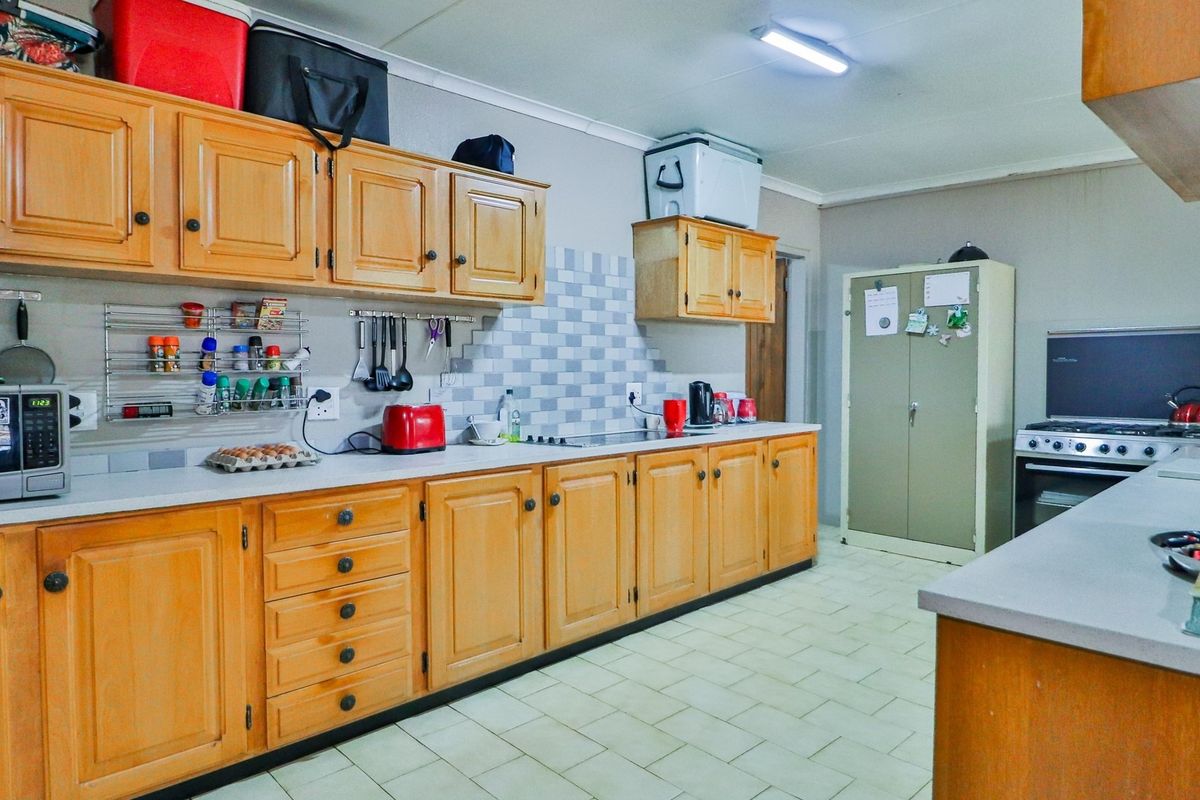 A functional kitchen featuring wooden cabinetry, tiled backsplash, and tiled flooring, providing ample storage and workspace for daily meal preparation.