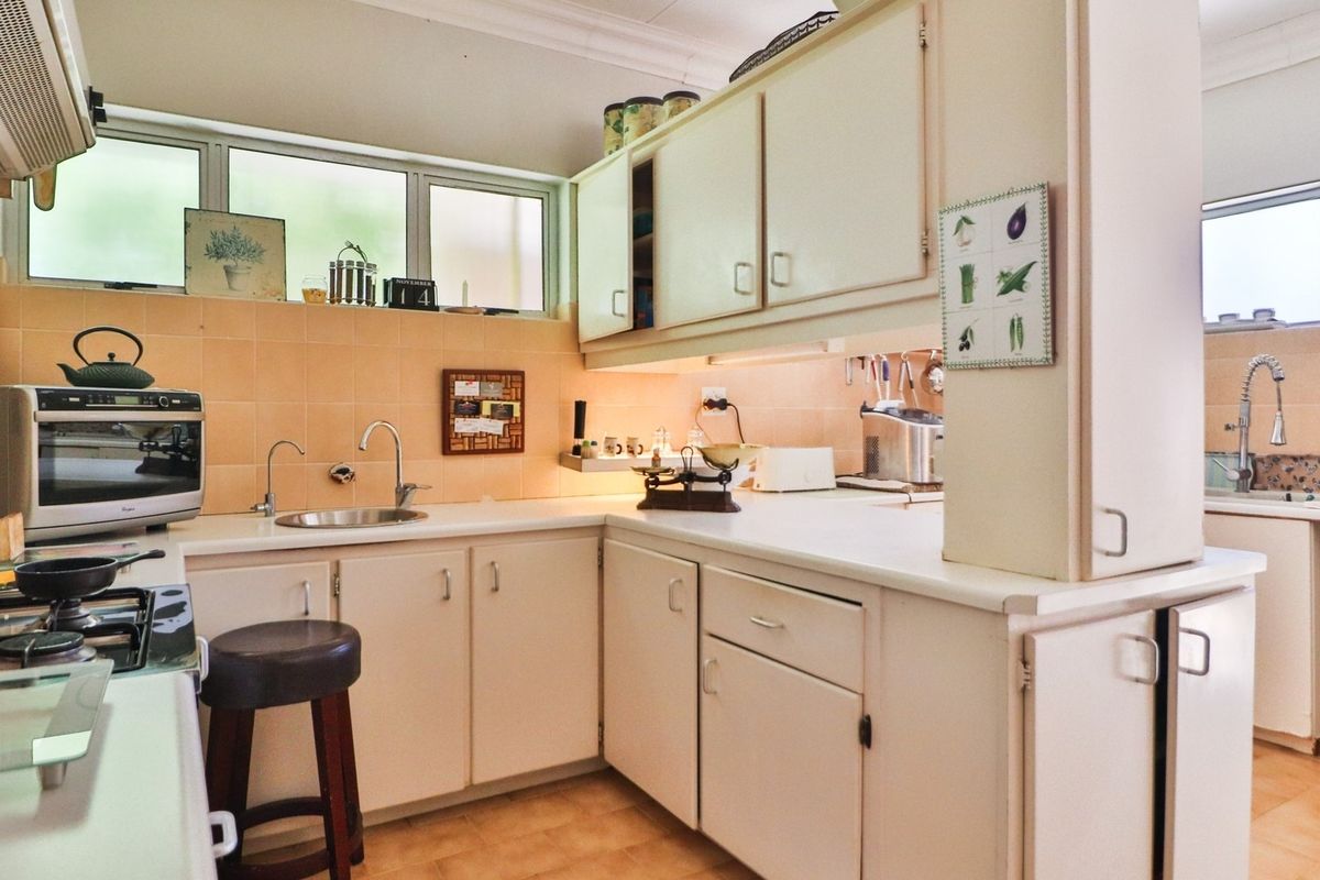 A functional kitchen featuring built-in cabinetry, a tiled backsplash, and a secondary prep area with a sink, offering a practical layout for daily use.
