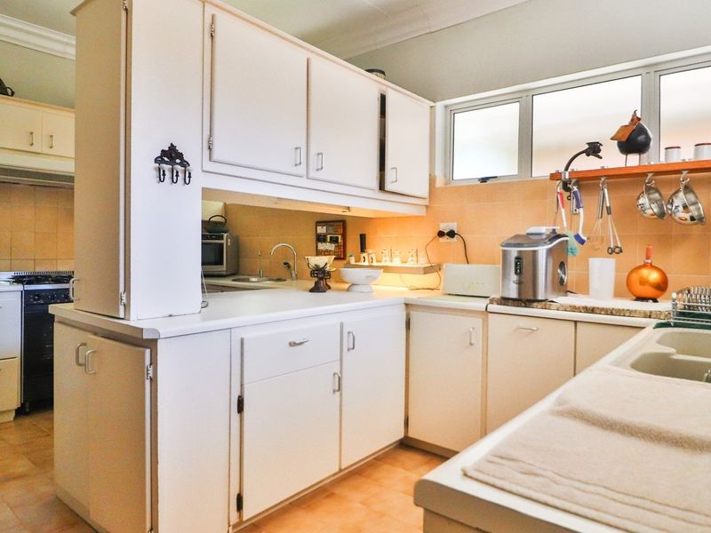 A functional kitchen featuring white cabinetry, tiled splashbacks, a double basin sink, and a built-in stove with an extractor fan.