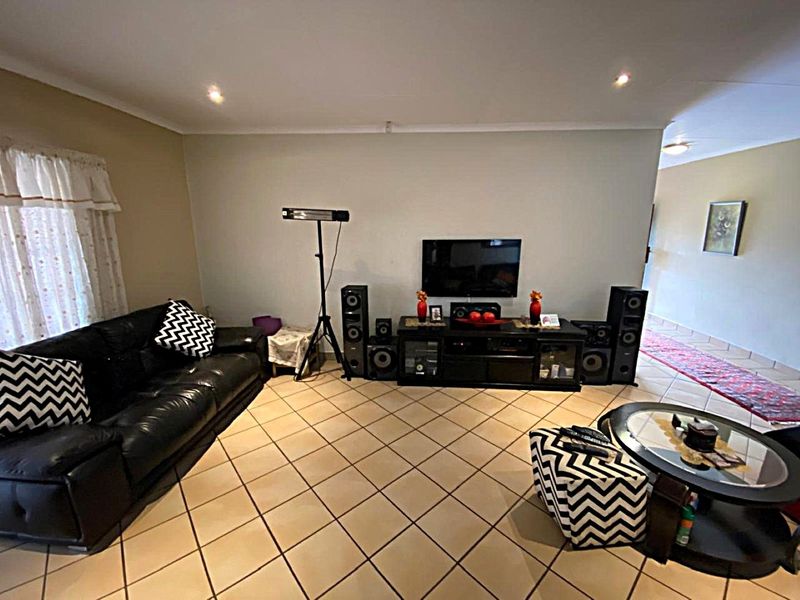 A spacious living room featuring neutral wall tones, ceramic floor tiles, and recessed downlighting, offering a comfortable and functional layout for relaxation.