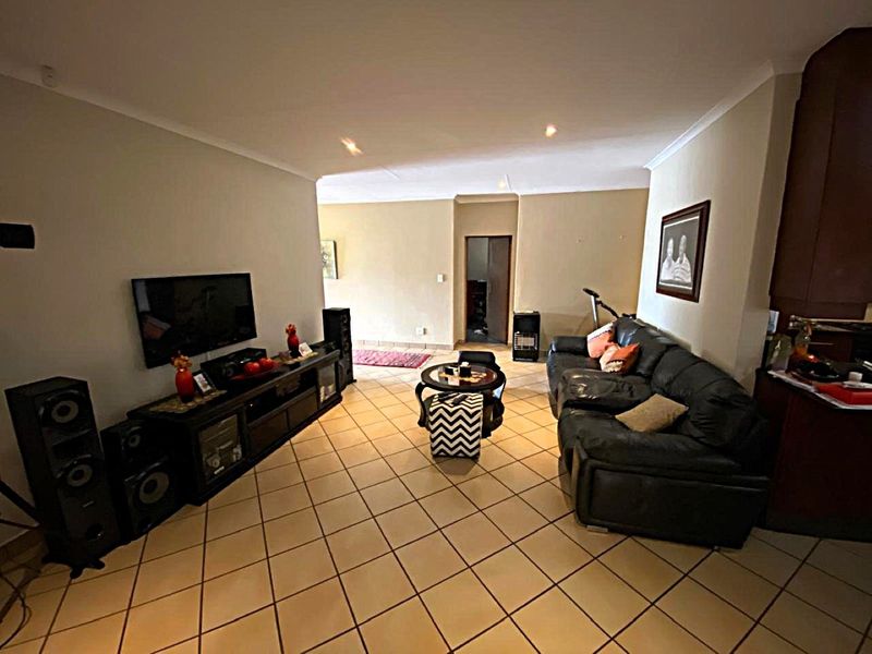A spacious living room featuring neutral wall tones, ceramic tiled flooring, and coved ceiling details, providing a comfortable and functional living area.