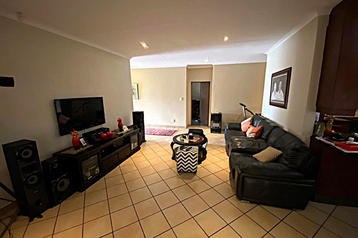 A spacious living room featuring neutral wall tones, ceramic tiled flooring, and coved ceiling details, providing a comfortable and functional living area.