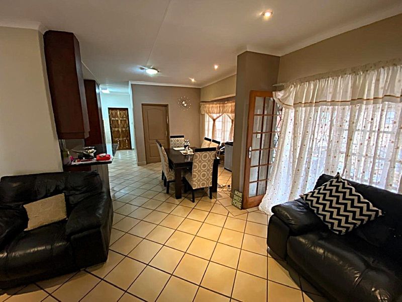 Open-plan living and dining area featuring tiled flooring, recessed lighting, and direct access to the exterior through classic french doors.