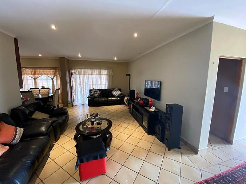 Spacious open-plan living and dining area featuring neutral wall tones, ceramic tiled flooring, and recessed downlighting throughout the main living space.