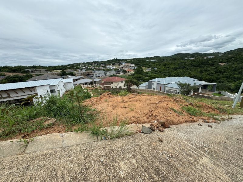 Elevated view overlooking a residential neighborhood and surrounding landscape from a vacant sloped plot.
