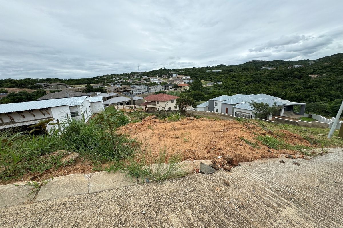 Elevated view overlooking a residential neighborhood and surrounding landscape from a vacant sloped plot.