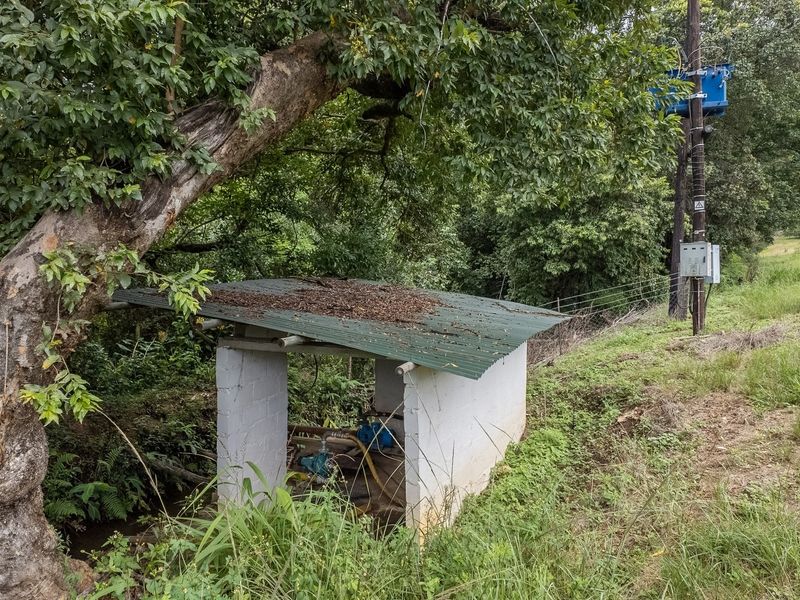 A small utility pump house structure located on the property grounds, featuring a corrugated metal roof and adjacent electrical infrastructure.