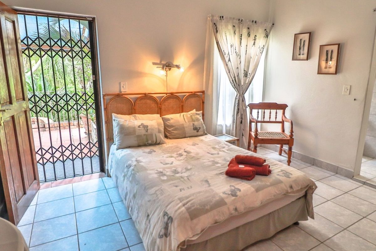 A bedroom featuring tiled flooring, a wall-mounted light fixture, and a security gate leading to an outdoor patio area.
