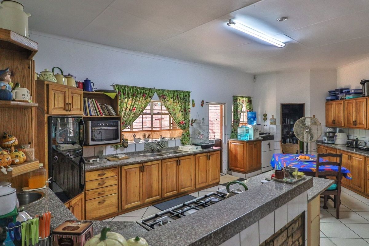 Spacious kitchen featuring extensive wooden cabinetry, a central island with a built-in gas hob, and tiled flooring throughout.