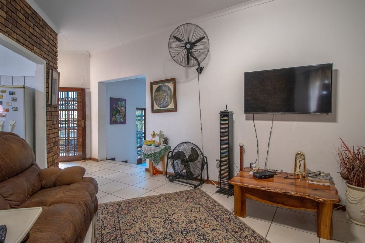 A living room featuring exposed brickwork, tiled flooring, and wall-mounted cooling fan, providing a functional and open living space.