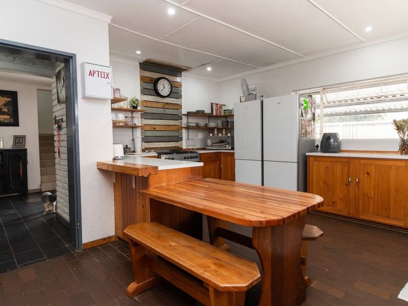 A functional kitchen featuring warm wooden cabinetry, a built-in gas stove, and a central wooden breakfast bar with integrated seating.