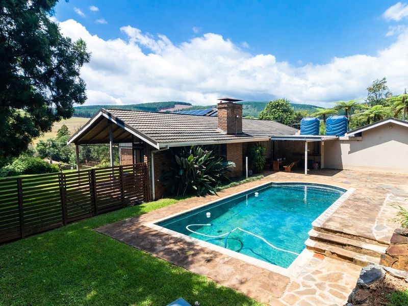 Outdoor pool area featuring stone paving, a brick chimney, and scenic views of the surrounding landscape.