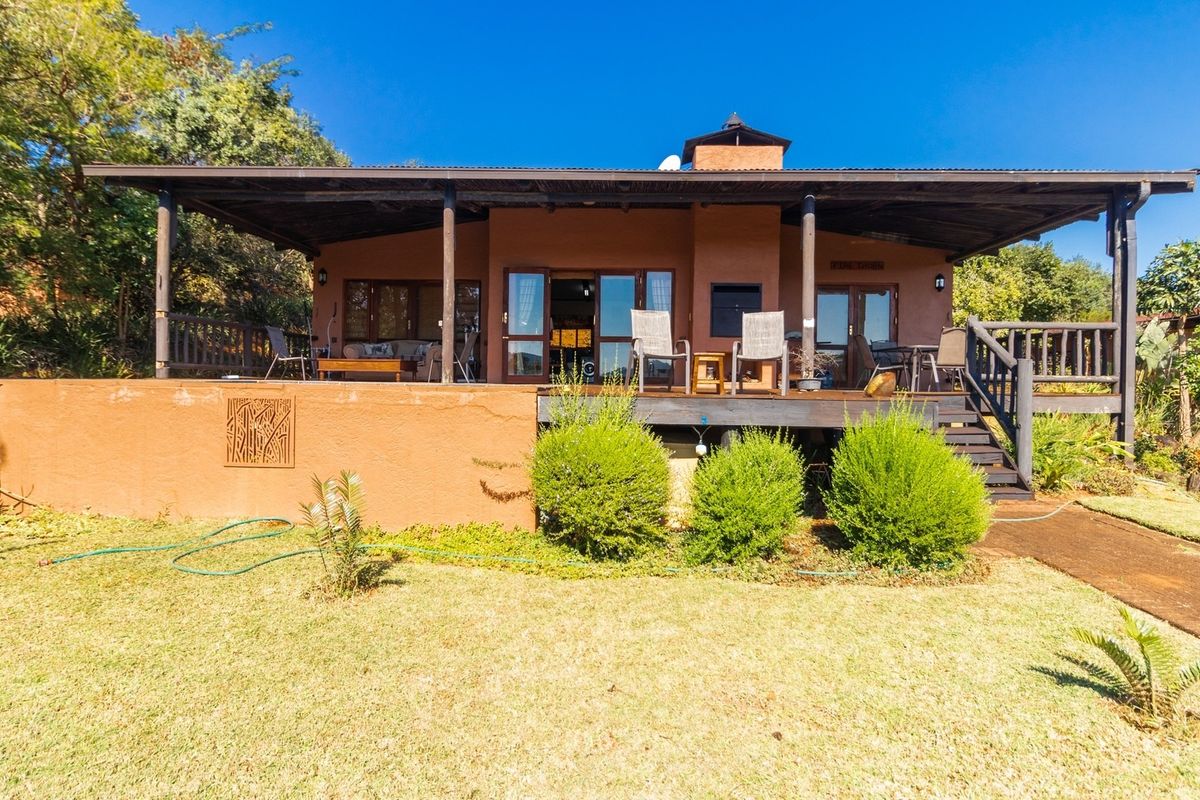 Rear view of the house featuring a spacious covered timber deck, built-in fireplace, and direct access to the garden through sliding glass doors.